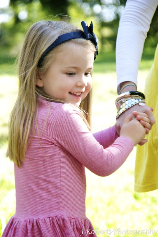 Little girl laughing holding mothers hand - family portrait photography